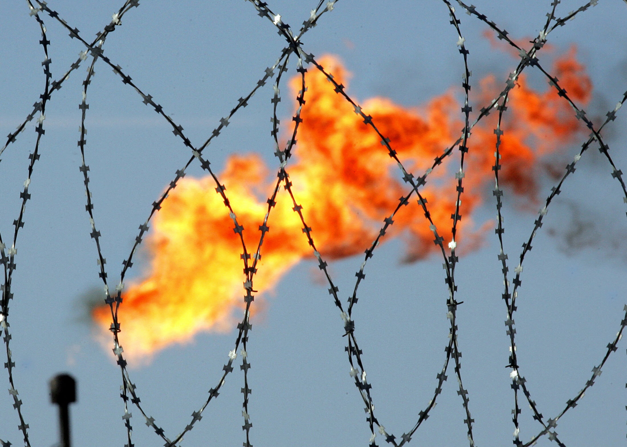 A gas flame is seen behind a barbed wire in the former at the Rosneft oil company production plant in Prirazlomnoye field, located in the Pechora Sea, south of Novaya Zemlya, Russia