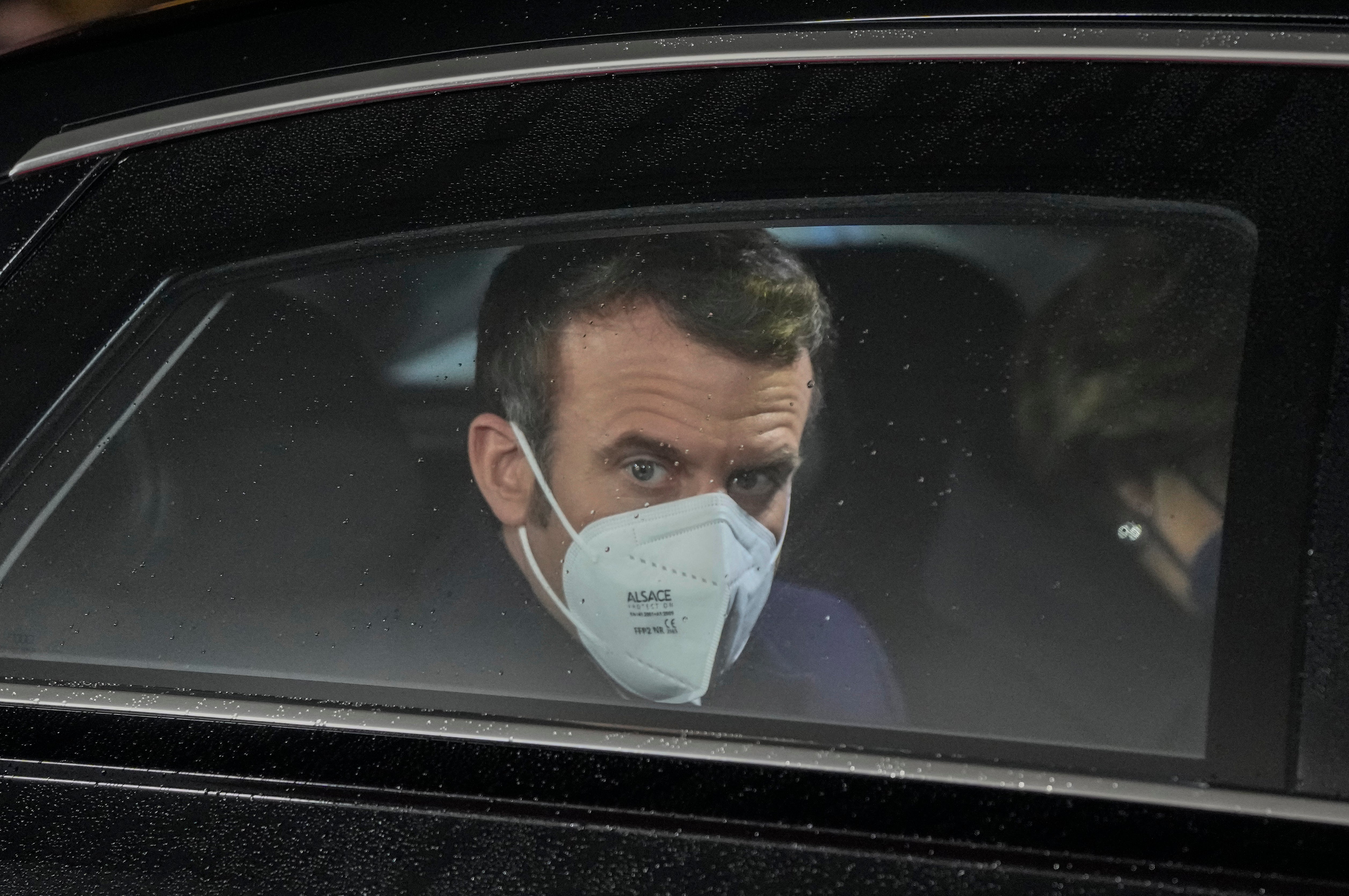 French President Emmanuel Macron looks out of her car window as he arrives for a meeting with German Chancellor Olaf Scholz at the chancellery in Berlin