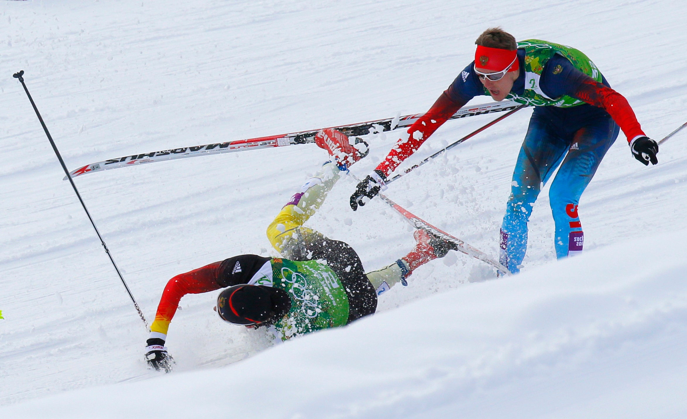 Germany’s Tim Tscharnke falls in front of Russia’s Nikita Kriukov at the 2014 Winter Olympics in Russia. Skiers and experts say manmade snow has a higher moisture content, making it ice up quickly