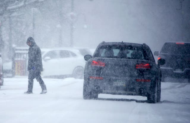 <p>A pedestrian crosses the street as a winter storm drops several inches of snow on Tuesday in Denver. A bomb cyclone is forecast to bring similar conditions to the East Coast this weekend</p>