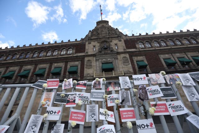 <p>Carteles, flores, retratos y cámaras afuera del Palacio Nacional de la Ciudad de México,</p>