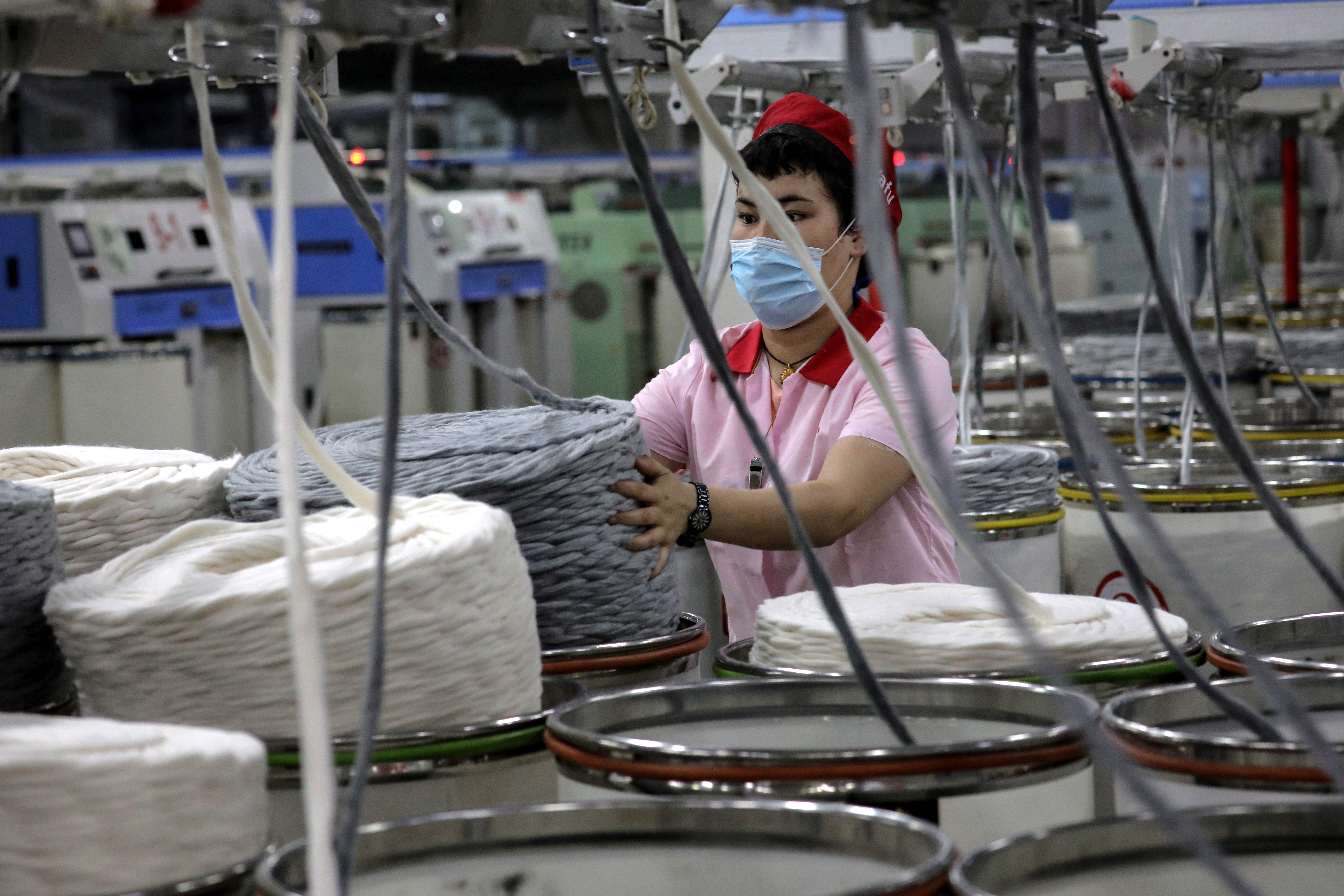 File: An ethnic minority worker operates cotton yarn machinery at Aksu Huafu textile limited company in Aksu, western China's Xinjiang Uyghur Autonomous Region