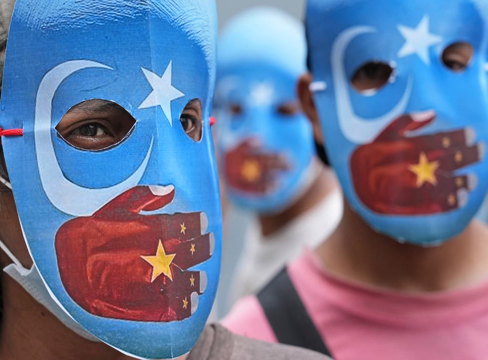 <p>File: Student activists wear masks with the colours of the pro-independence East Turkestan (or Uyghur flags) during a rally to protest the Beijing 2022 Winter Olympic Games </p>