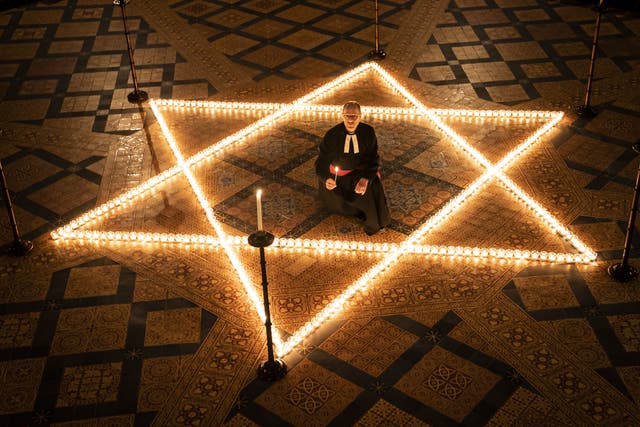 The Reverend Canon Michael Smith helps light six hundred candles in the shape of the Star of David (Danny Lawson/PA)