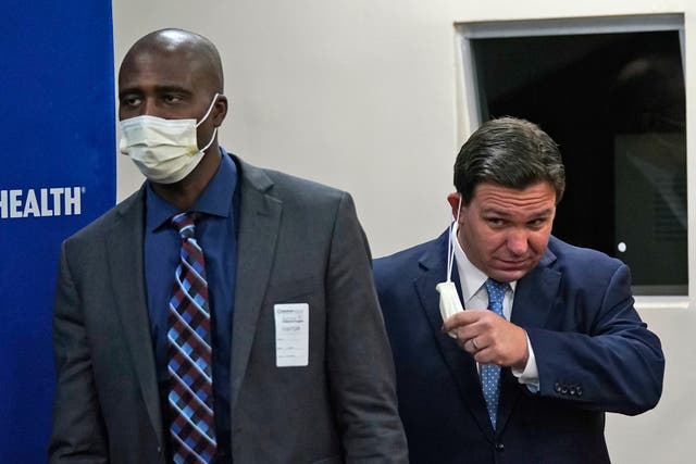 <p>Florida Gov. Ron DeSantis, right, takes off his mask, worn to help prevent the spread of COVID-19, as he arrives at a news conference with Florida Surgeon Gen. Dr. Joseph A. Ladapo, Monday, Jan. 3, 2022</p>