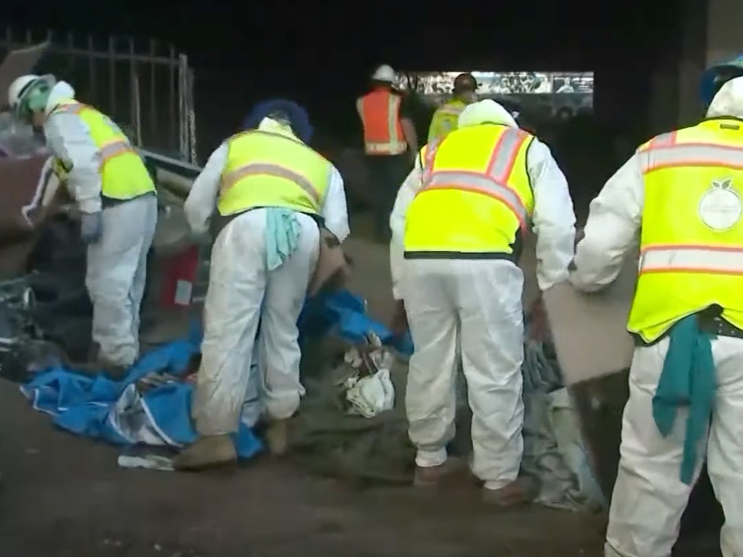 Los trabajadores estatales en Los Ángeles limpian un campamento para personas sin hogar cerca de la autopista 405 y el estadio SoFi antes del Super Bowl 2022.