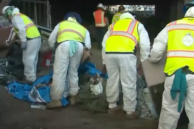 Los trabajadores estatales en Los Ángeles limpian un campamento para personas sin hogar cerca de la autopista 405 y el estadio SoFi antes del Super Bowl 2022.