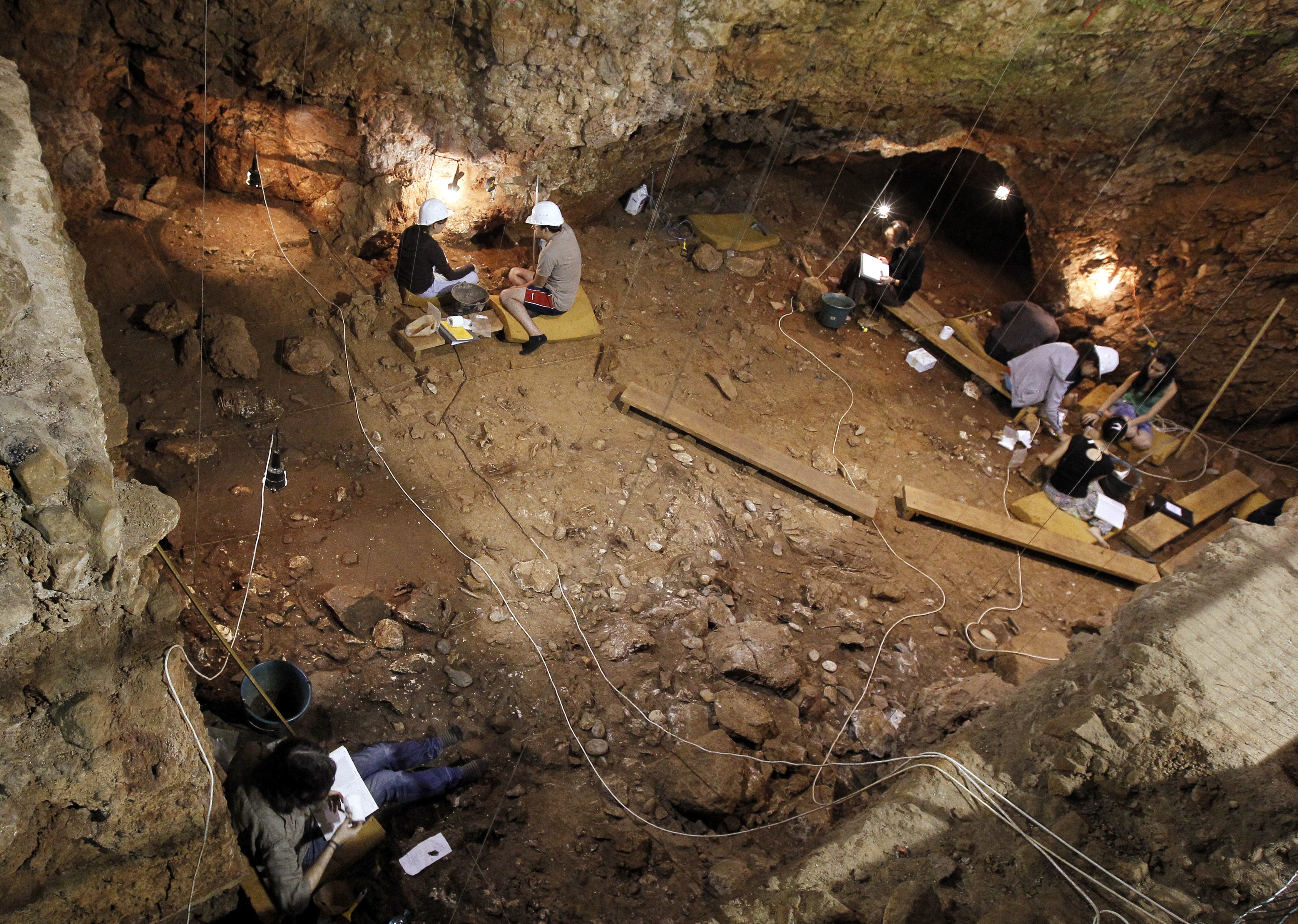 Volunteers dust the ground on August 18, 2011, in the coastal cave of Lazaret near Nice, southern France, where a 170,000 year old Homo erectus forehead bone has been discovered
