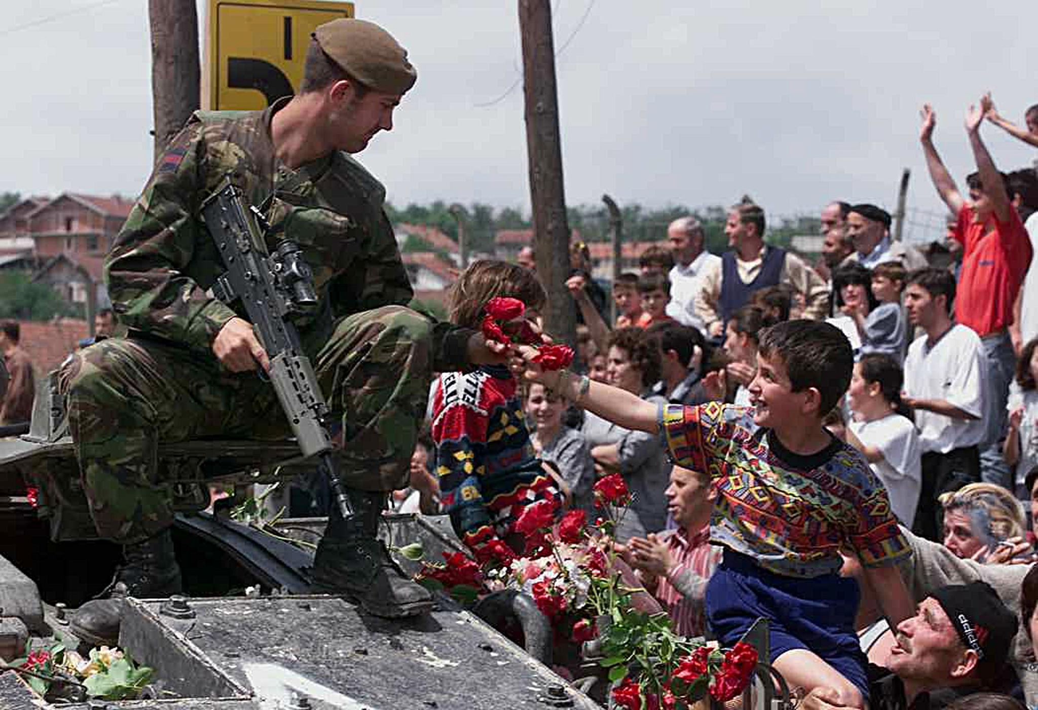 An ethnic Albanian boy gives red roses to a British soldier as first Nato troops are deployed in Pristina, 13 June 1999