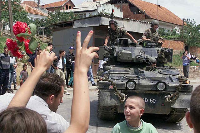 <p>Ethnic Albanian people flash the victory sign and celebrate in front of a British Nato tank, its gun barrel decorated with flowers, as the first Nato troops are deployed in Kosovo’s capital Pristina, 13 June 1999</p>