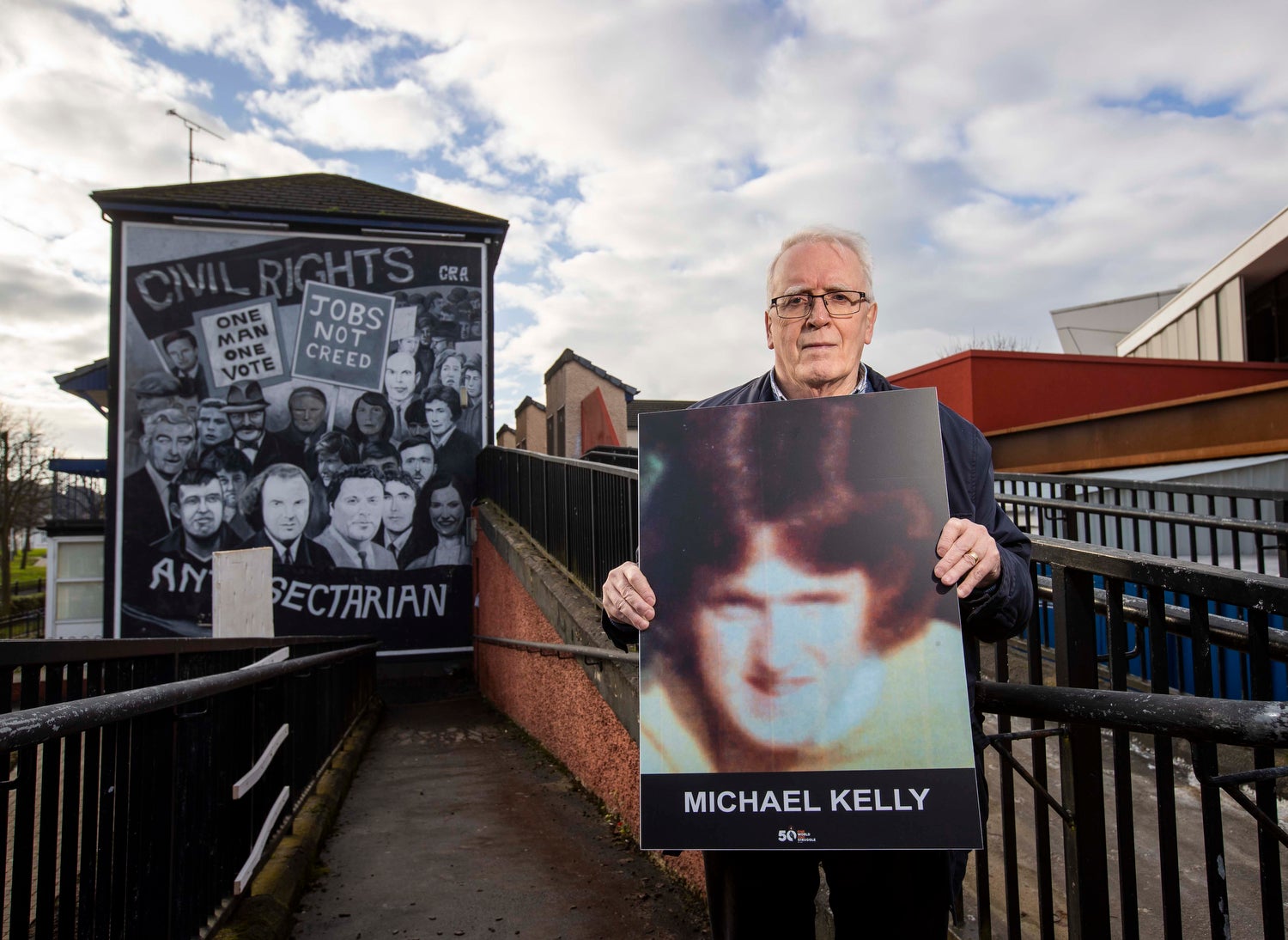 John Kelly brother of Michael Kelly killed on Bloody Sunday in Derry’s Bogside in 1972, stands holding an image of his brother beside the Civil Rights mural in Derry. PA Photo. Picture date: Monday January 24 2022. See PA story ULSTER BloodySunday. Photo credit should read: Liam McBurney/PA Wire