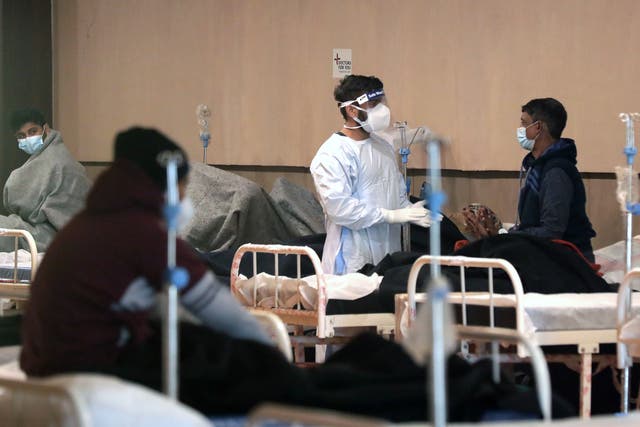 <p>An Indian doctor in PPE checks on a patient at a Covid-19 isolation ward in Delhi </p>
