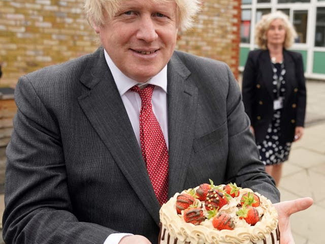 <p> Boris Johnson holding a birthday cake presented to him by the staff during a socially distanced visit to Bovingdon Primary School</p>