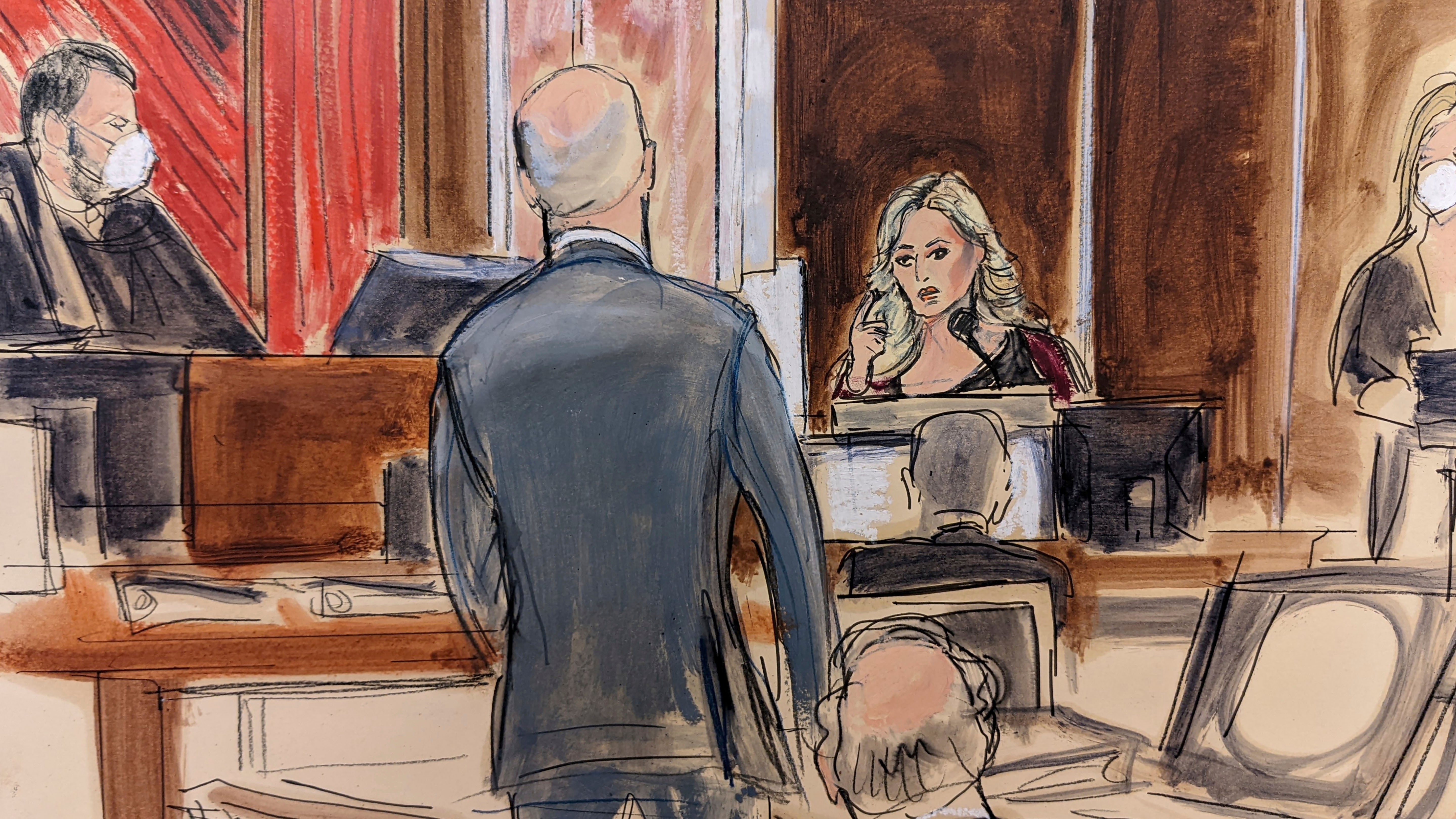 Stormy Daniels testifying on the witness stand, at right, points to Michael Avenatti, standing at center. Judge Jesse Furman presides on the bench