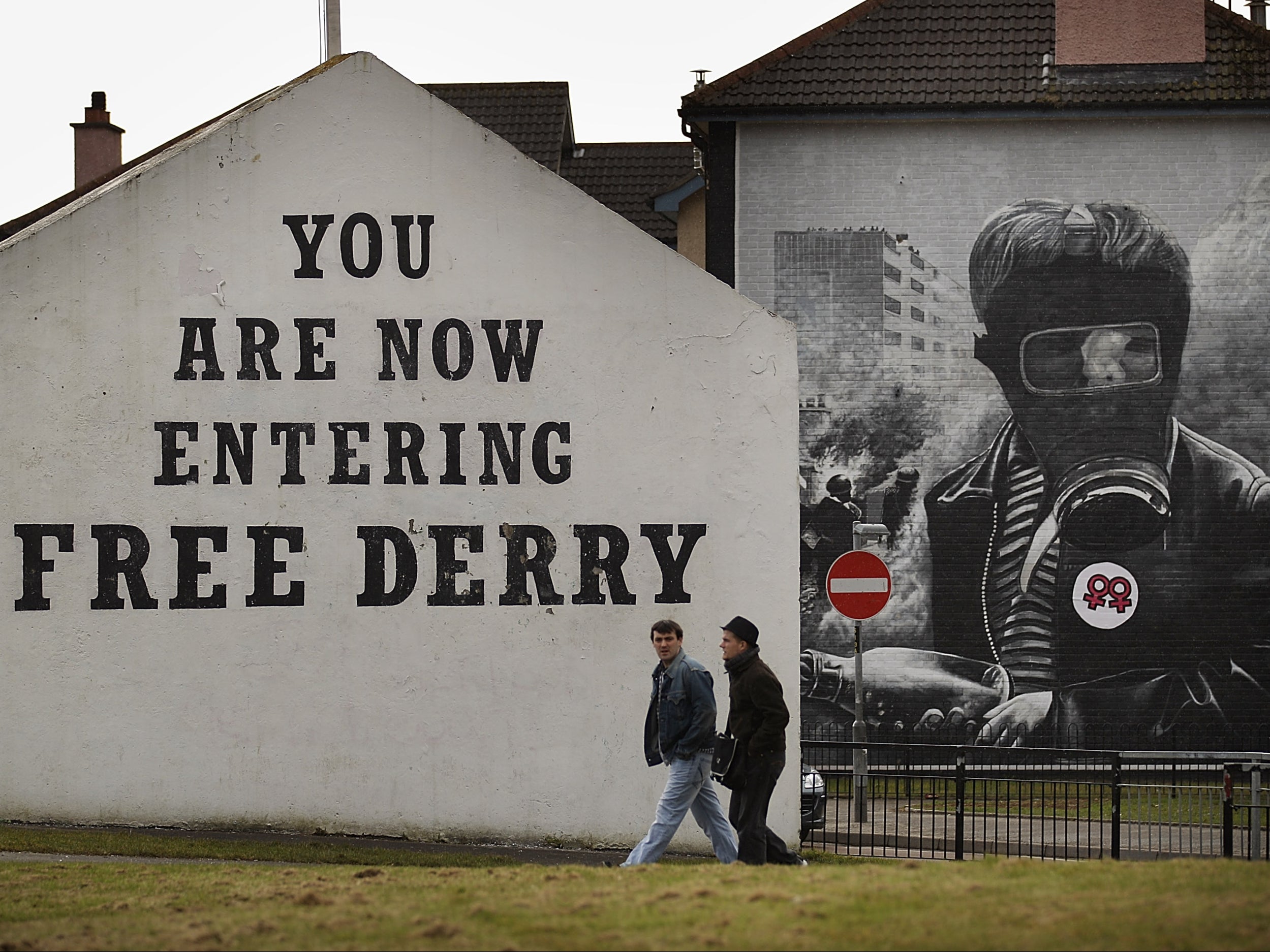 Two men walk past Free Derry Corner in the Catholic Bogside area of Derry in Northern Ireland