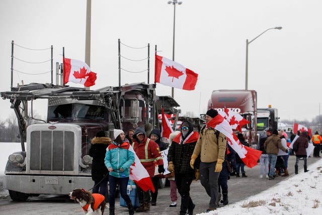 <p>Supporters of the Freedom Convoy of truckers driving from British Columbia to Ottawa in protest against a Covid-19 vaccine mandate gather near a highway overpass outside of Toronto, Ontario</p>