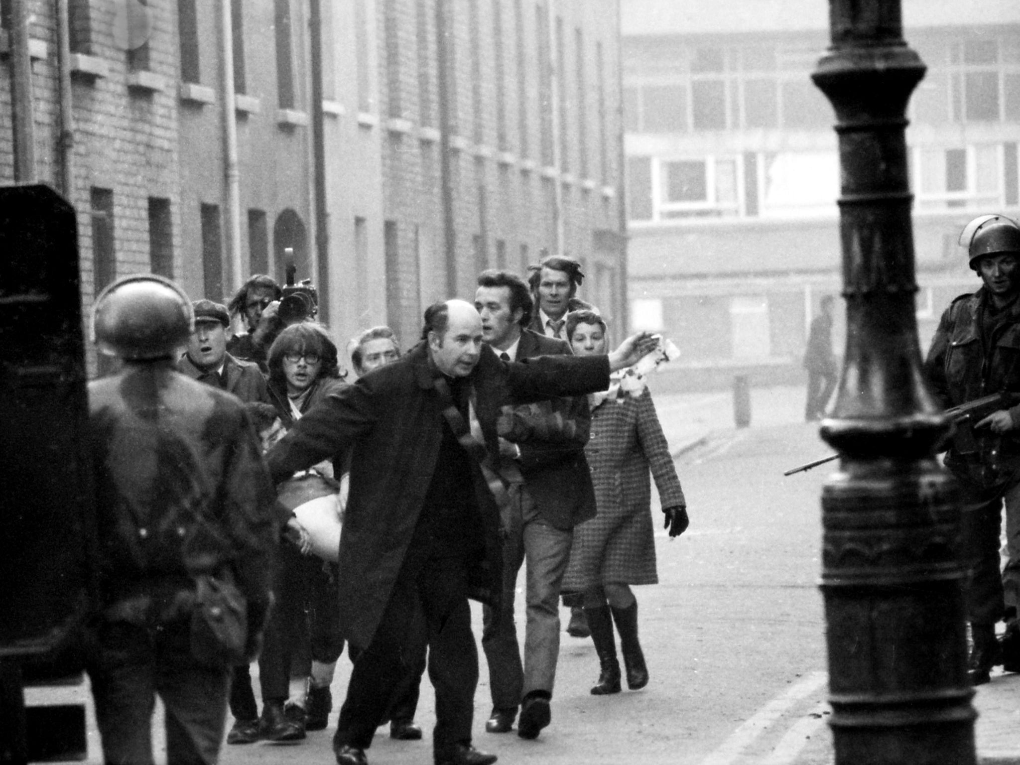 Father Edward Daly, later Bishop of Derry, waves a blood-stained white handkerchief at soldiers as a mortally wounded protester is carried away, on 30 January 1972
