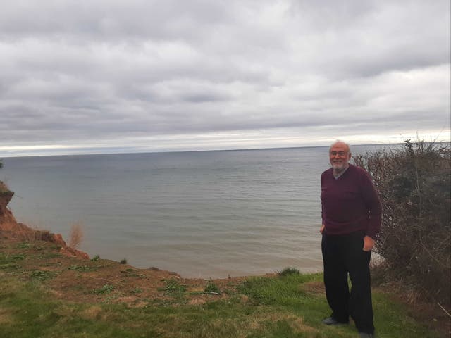 <p>Paul Griew in his Devon garden, which has lost around 20 metres to the sea</p>