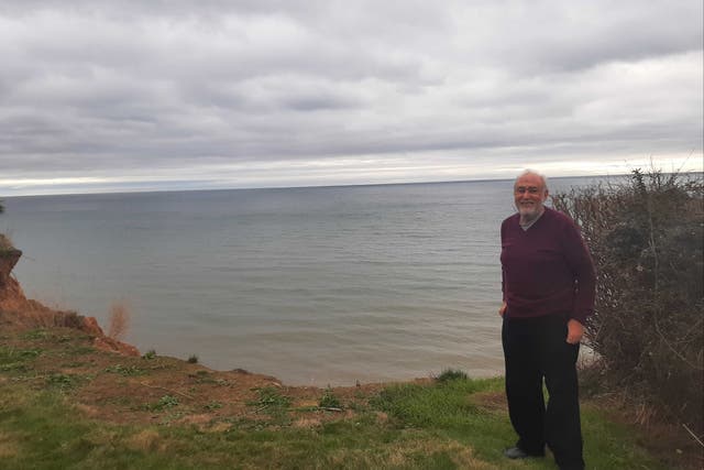 <p>Paul Griew in his Devon garden, which has lost around 20 metres to the sea</p>