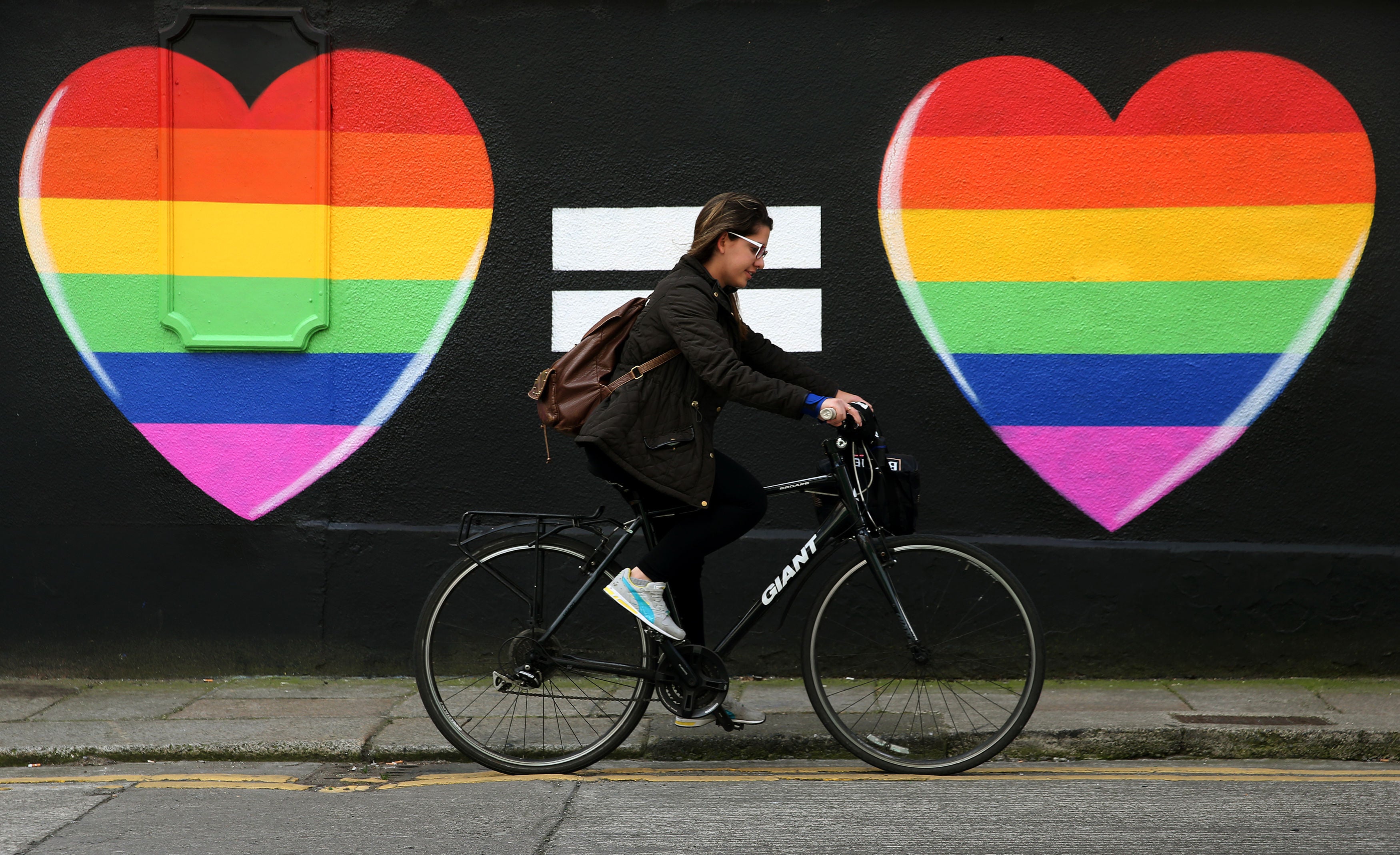 A woman cycles past a marriage equality mural in the Liberties area of Dublin (Brian Lawless/PA)
