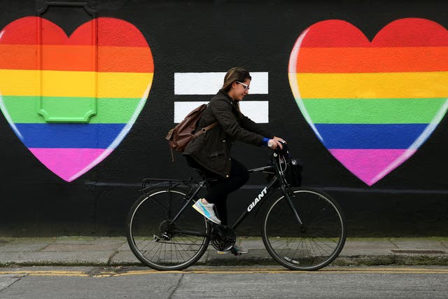 A woman cycles past a marriage equality mural in the Liberties area of Dublin (Brian Lawless/PA)
