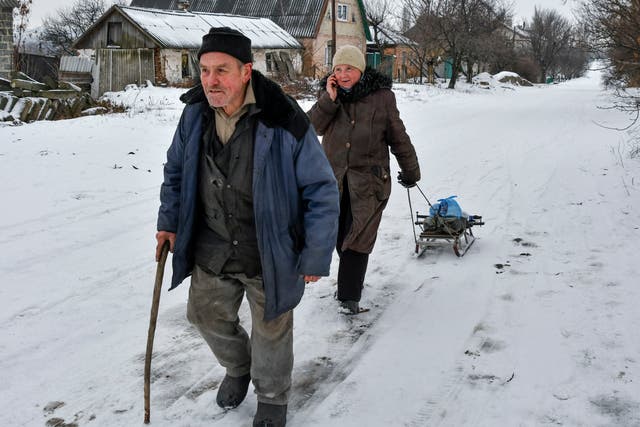 Local residents walk along a street near the front line with Russia-backed separatists in Verkhnotoretske village, Yasynuvata district in Donetsk region, eastern Ukraine (Andriy Andriyenko/AP)