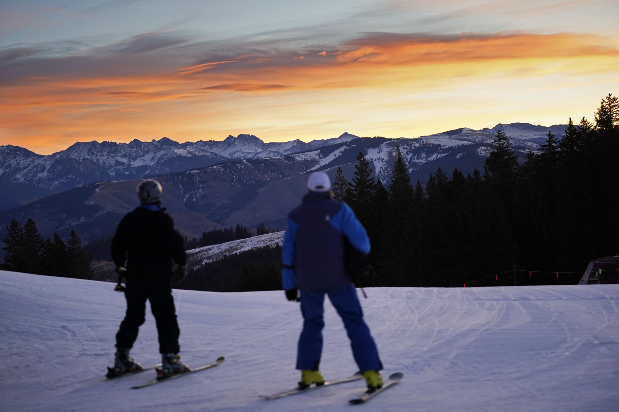 Skiers look east to the high peaks of the Rocky Mountains while skiing on man-made snow, Dec. 4, 2021, in Beaver Creek, Colo.