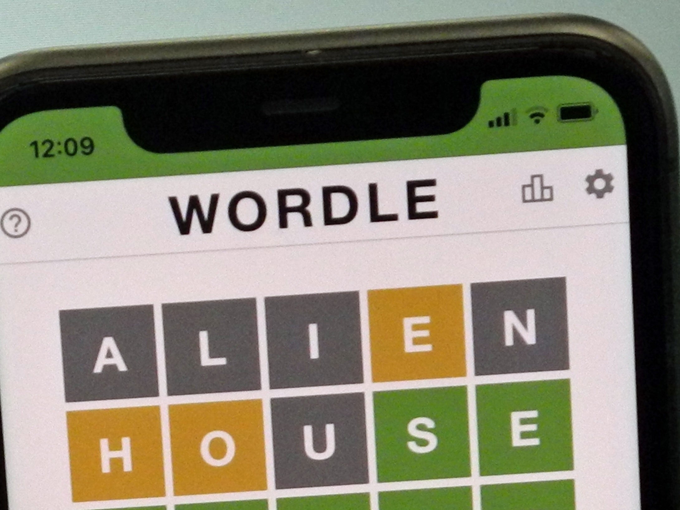 A mobile phone shows the screen of the popular online game Wordle