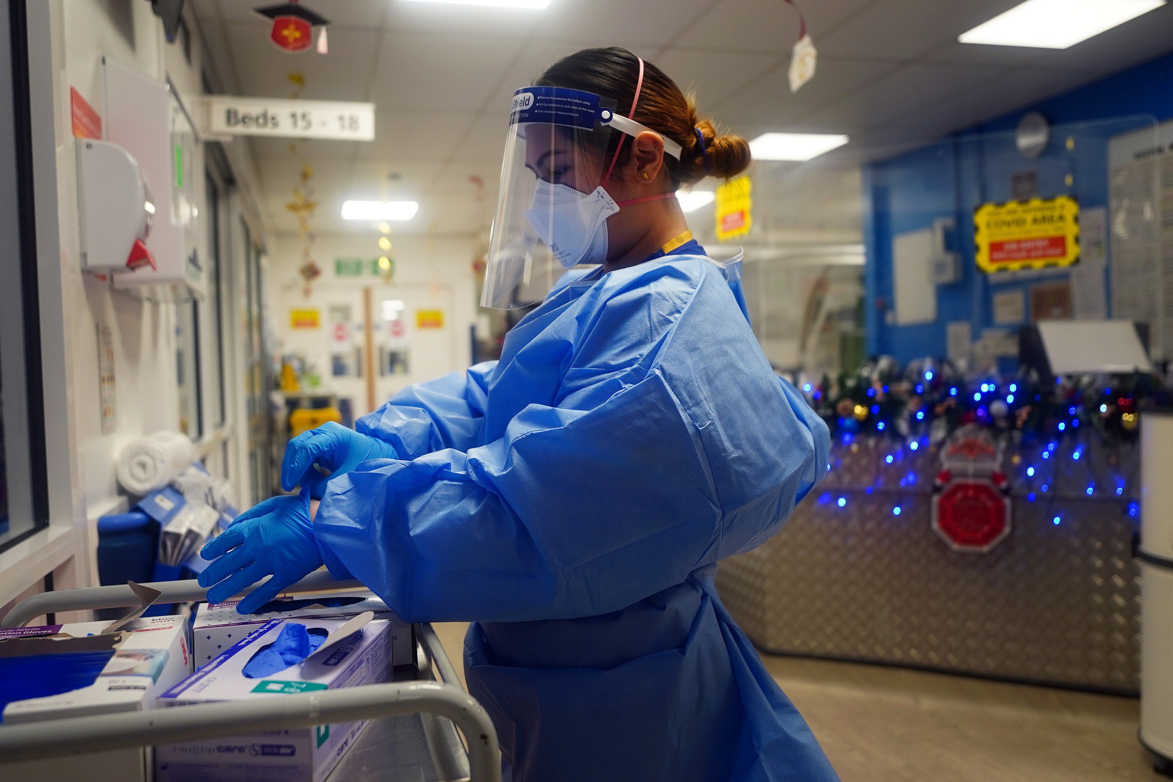 A NHS nurse putting on PPE (PA)