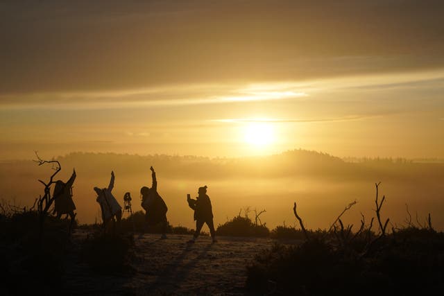 People practise yoga as the sun rises near Fordingbridge in the New Forest, Hampshire (Andrew Matthews/PA)