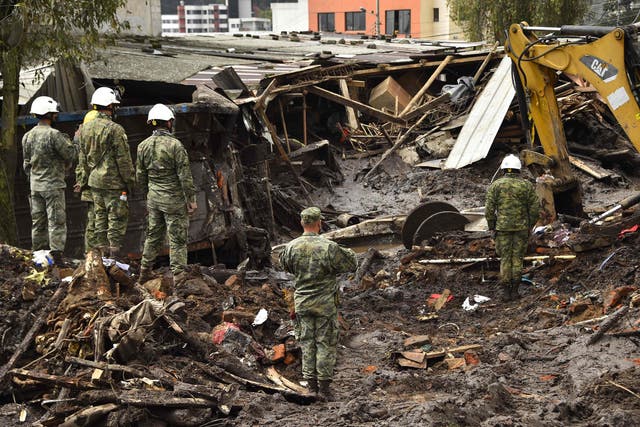 <p>Army members watch a backhoe digger searching for victims amid mud in La Gasca neighborhood, northern Quito, on February 1, 2022</p>