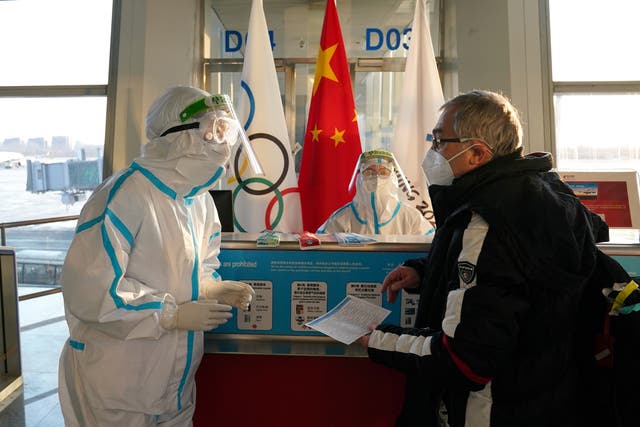 Airport staff wearing hazmat suits assist passengers at Beijing International Airport (Andrew Milligan/PA)
