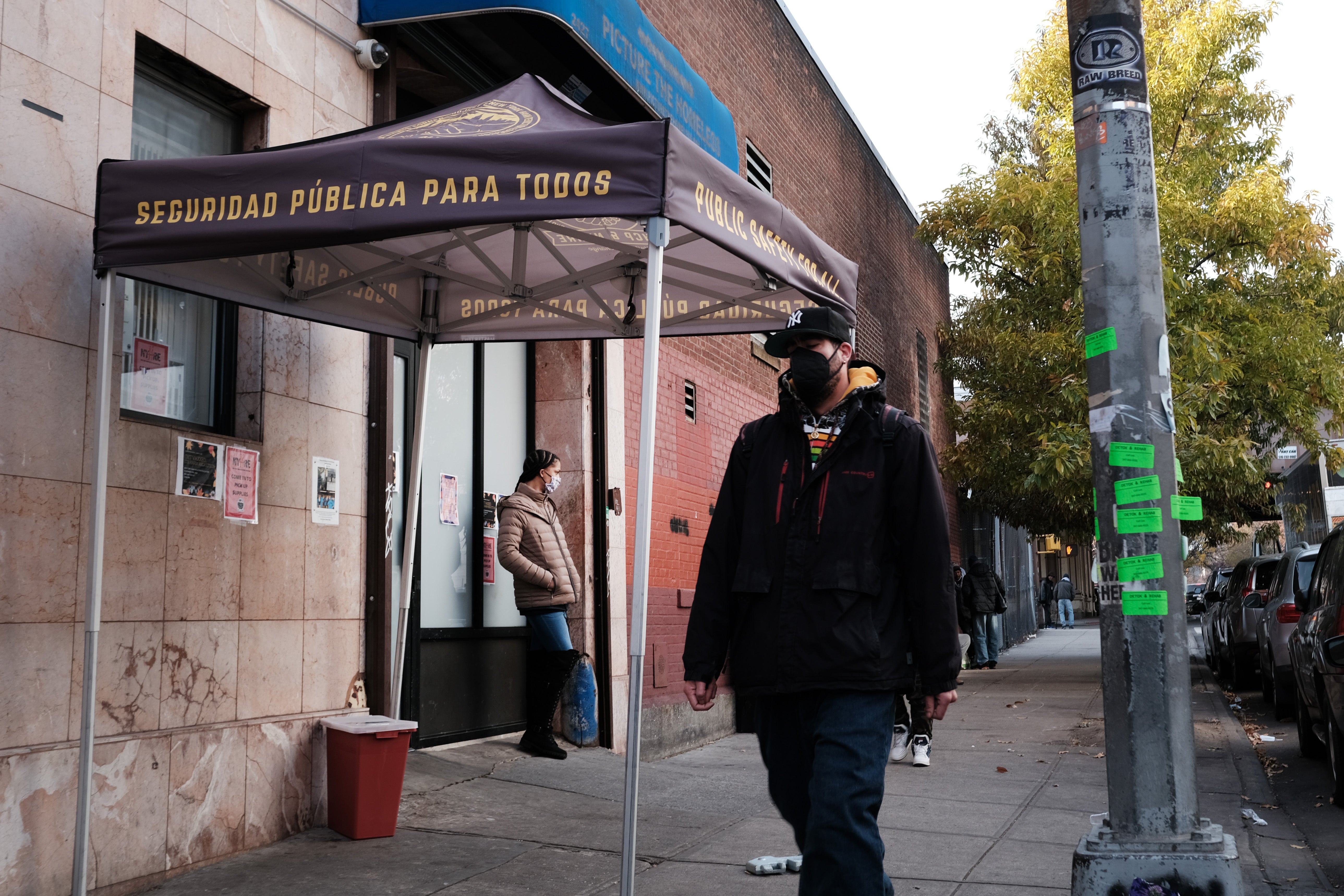 People walk past an East Harlem health clinic that houses an overdose prevention room for drug users to consume under supervision