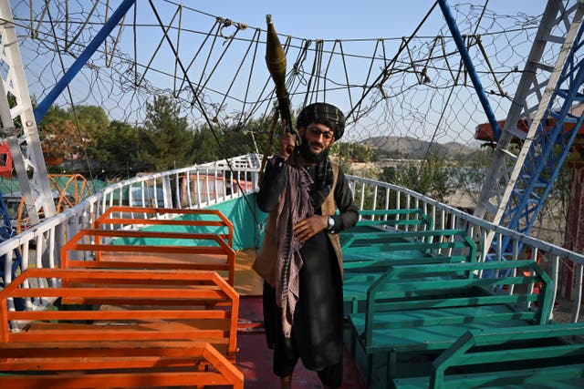 <p>A Taliban fighter carrying a rocket propelled grenade (RPG) launcher stands on pirate ship ride in a fairground at Qargha Lake on the outskirts of Kabul, 28 September 2021</p>