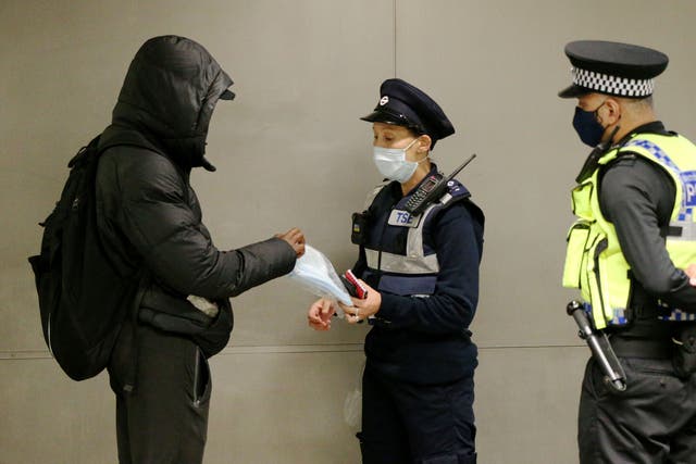 A man is given a face mask to wear after being issued with a fine for not being in possession of and not wearing a face mask (Jonathan Brady/PA)