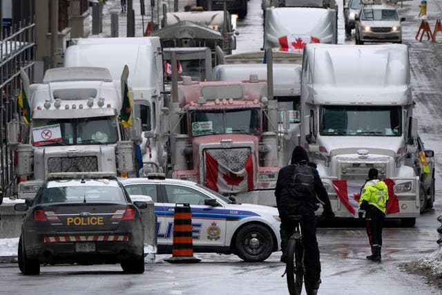 <p>A cyclist rides towards a police barricade where trucks are lined up near Parliament hill on Wednesday, Feb. 2, 2022 in Ottawa</p>