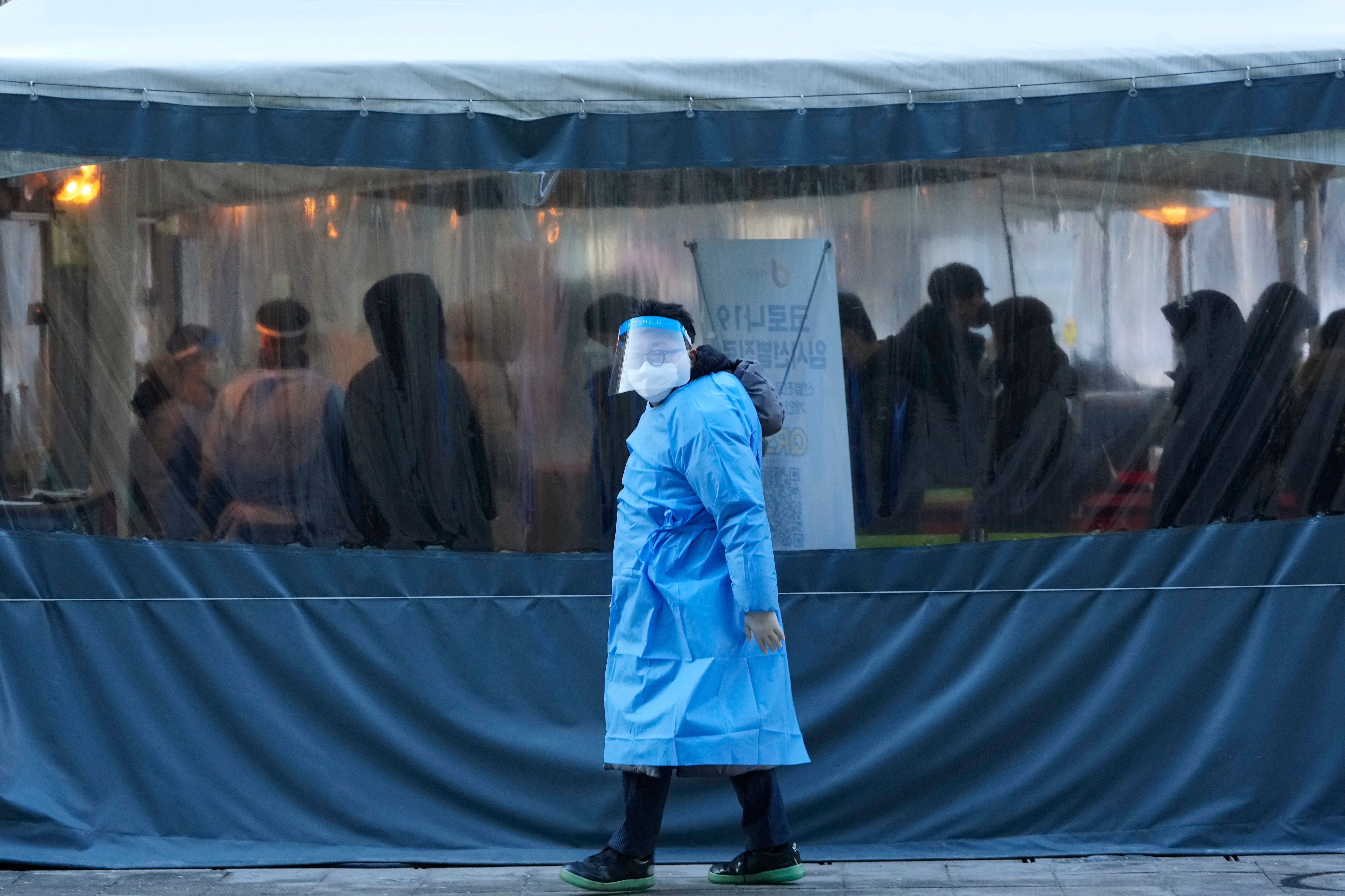 A medical worker passes by people as they wait for their coronavirus tests at a makeshift testing site in Seoul, South Korea