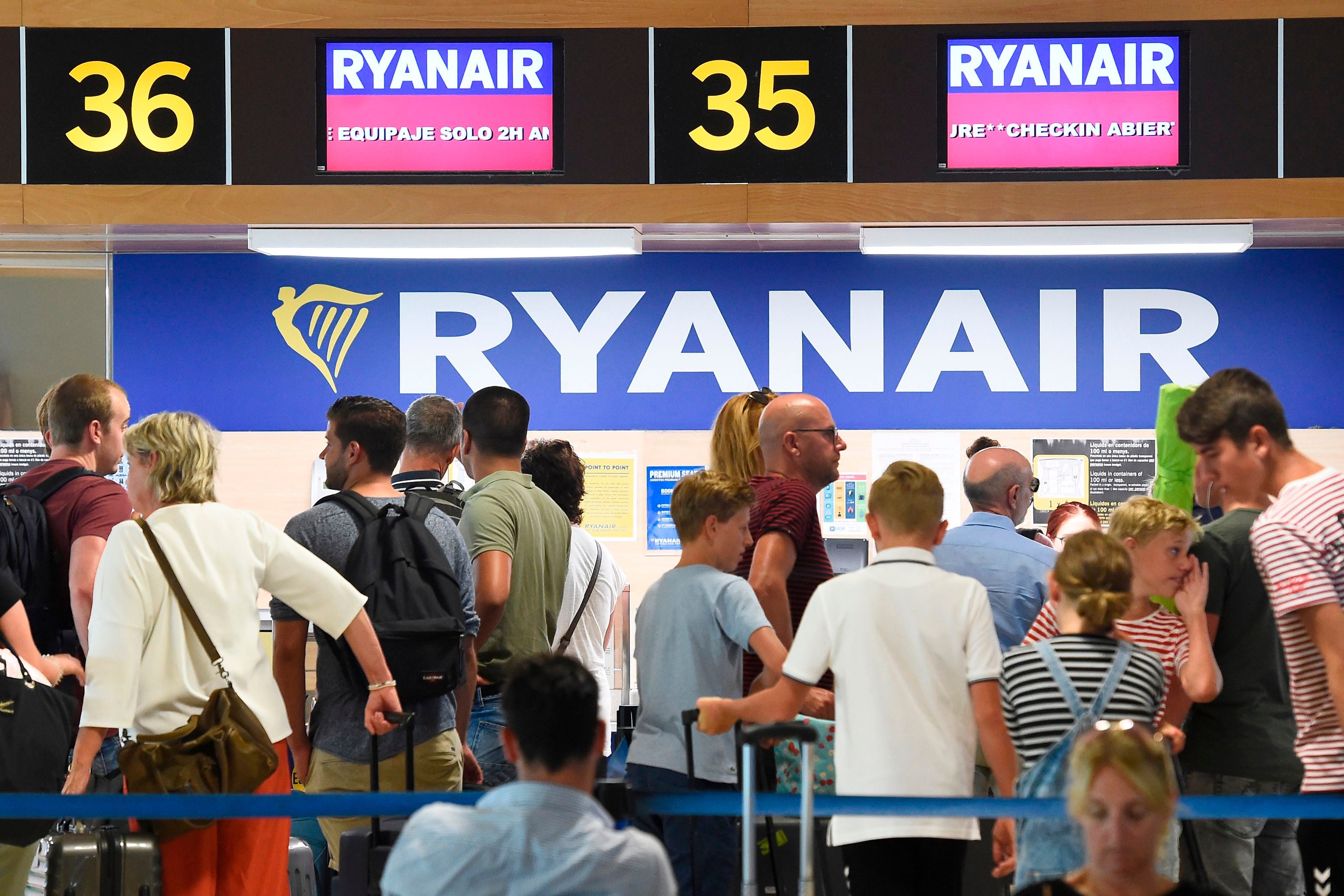 Passengers queue at a Ryanair check-in counter in Valencia