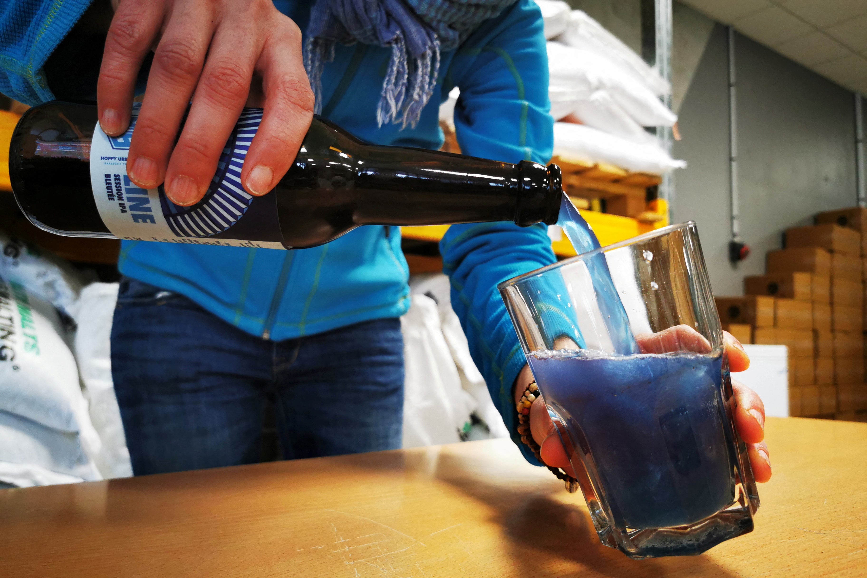 A Hoppy Urban Brew (HUB) worker pours a bottle of the Line blue beer, which is made with spirulina algae, in n Roubaix near Lille, France, 31 January 2022