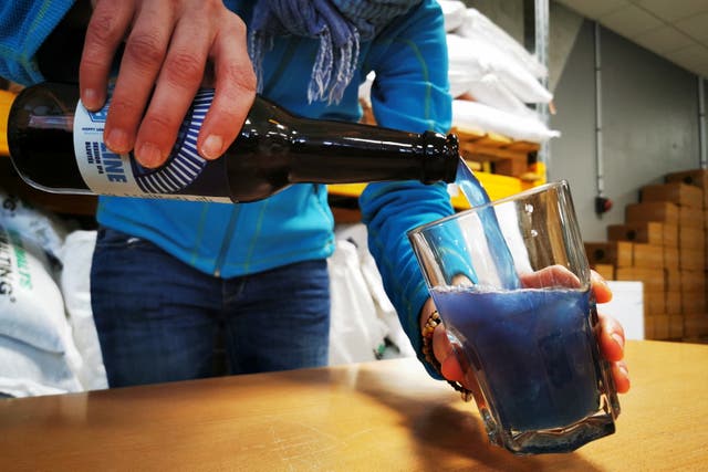 <p>A Hoppy Urban Brew (HUB) worker pours a bottle of the Line blue beer, which is made with spirulina algae, in n Roubaix near Lille, France, 31 January 2022</p>