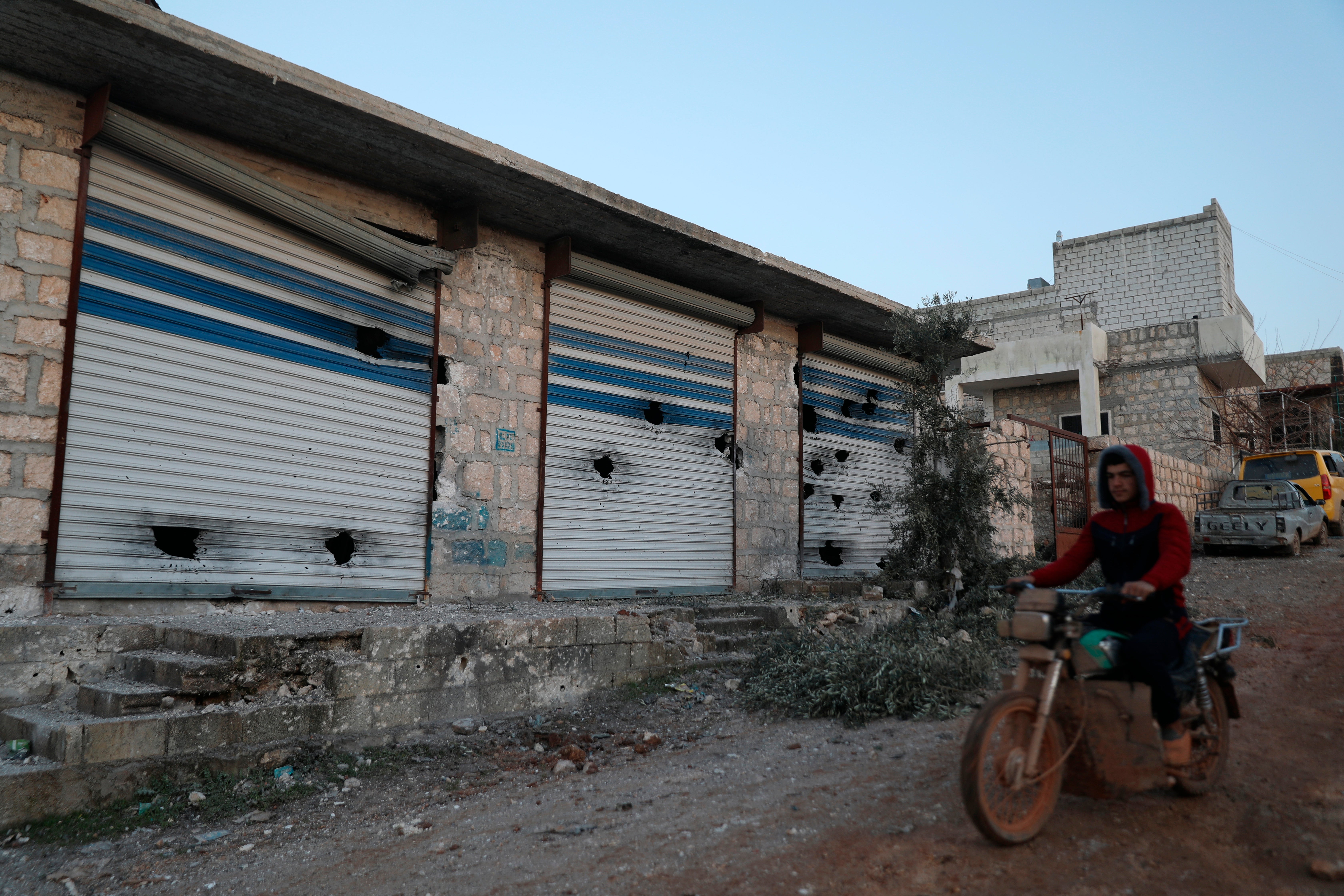 A Syrian man rides his motorcycle along damaged shops after an operation by the U.S. military in the Syrian village of Atmeh in Idlib province, Syria, Thursday, Feb. 3, 2022