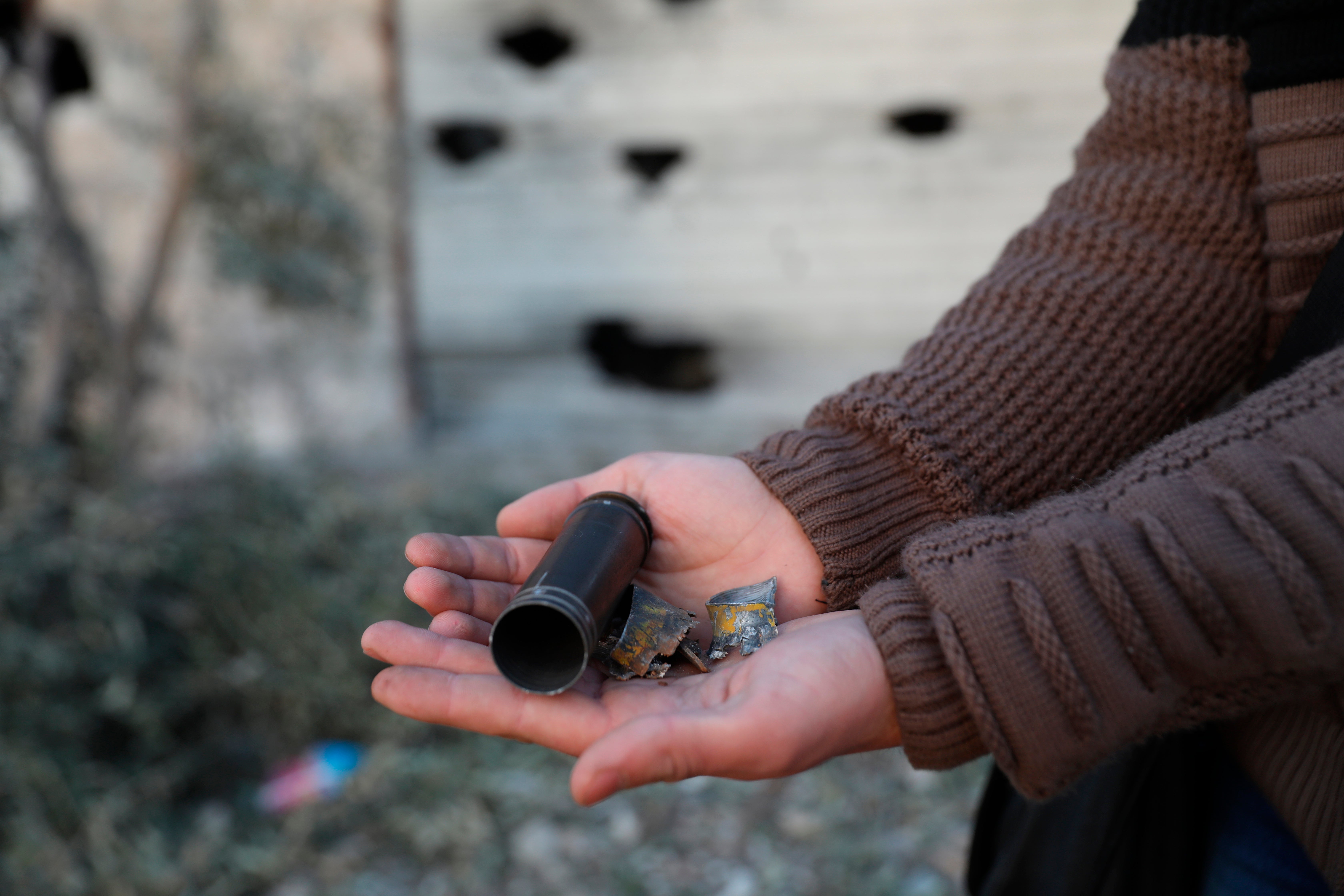 A child shows an empty bullet shell outside a destroyed house after an operation by the U.S. military in the Syrian village of Atmeh, in Idlib province, Syria, Thursday, Feb. 3, 2022