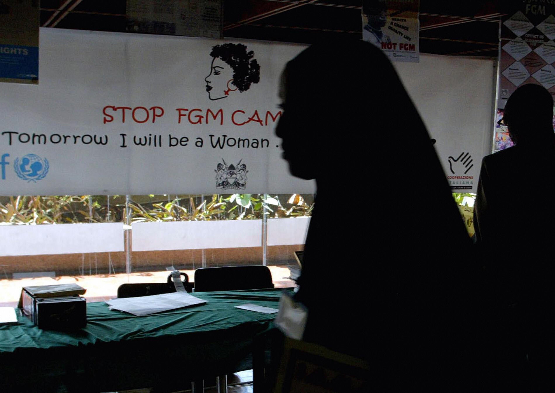 Woman walks past banner against female genital mutilation in Nairobi