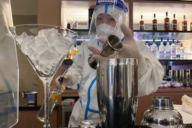 <p>A bartender in personal protective equipment (PPE) prepares a cocktail in a hotel for journalists and officials of the Beijing 2022 Winter Olympics, in Zhangjiakou, China</p>