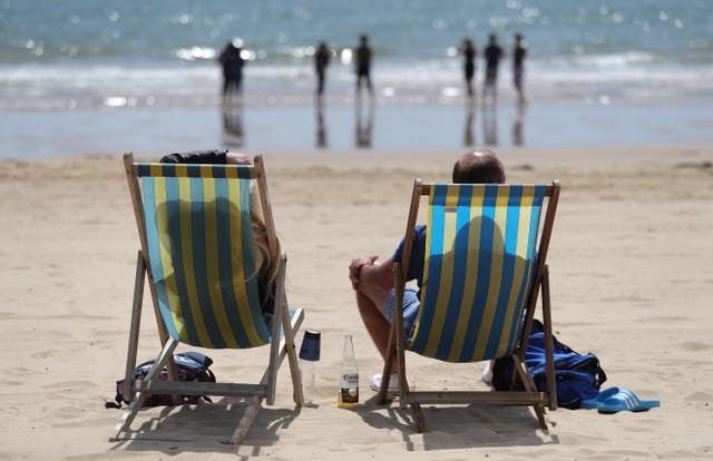 <p>People enjoy the sun on a British beach </p>