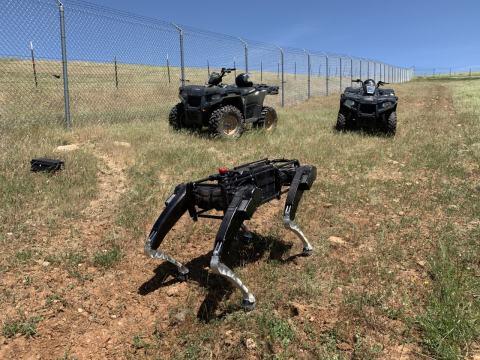 A robot dog operating alongside ATVs in the southwest US