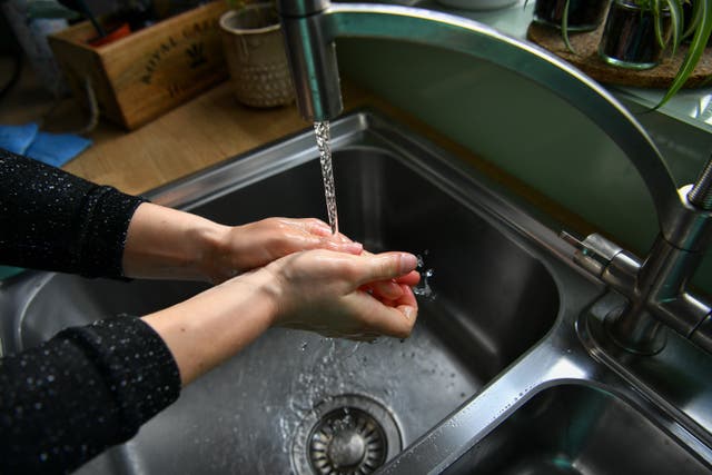 <p>A woman washes her hands. </p>