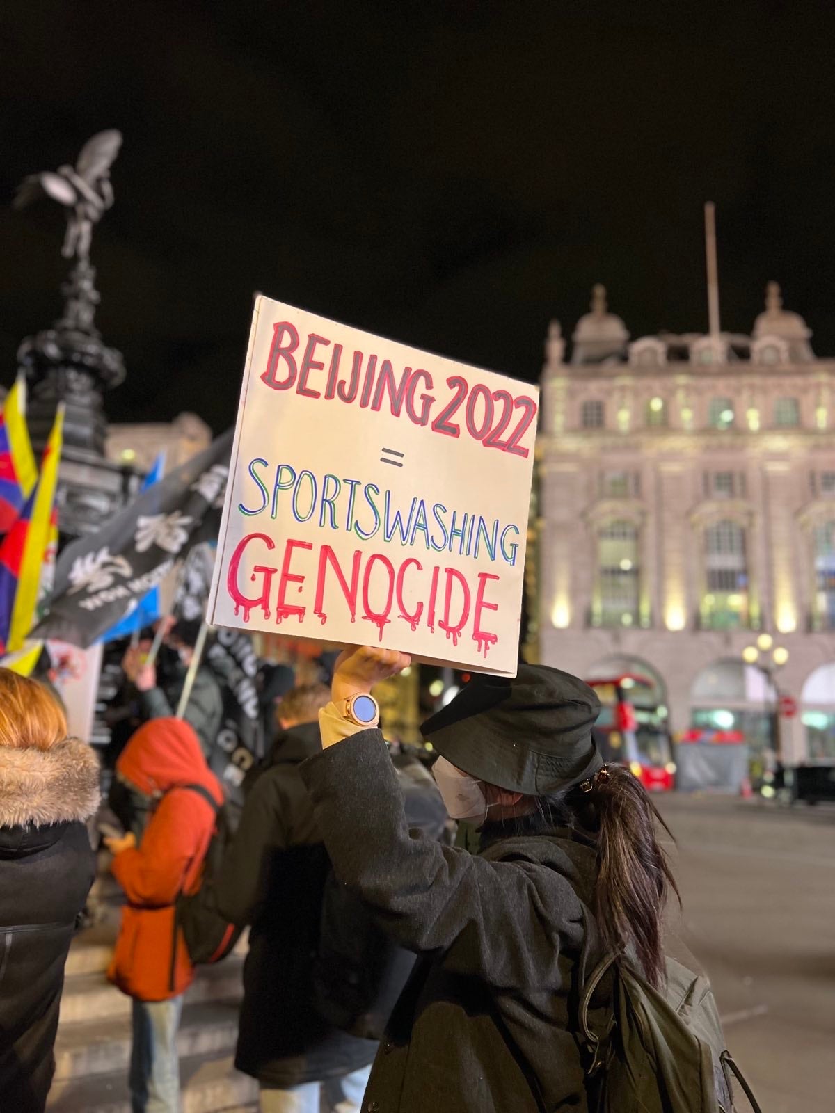 A protester in central London holds a placard accusing China of sportswashing over the Winter Olympics