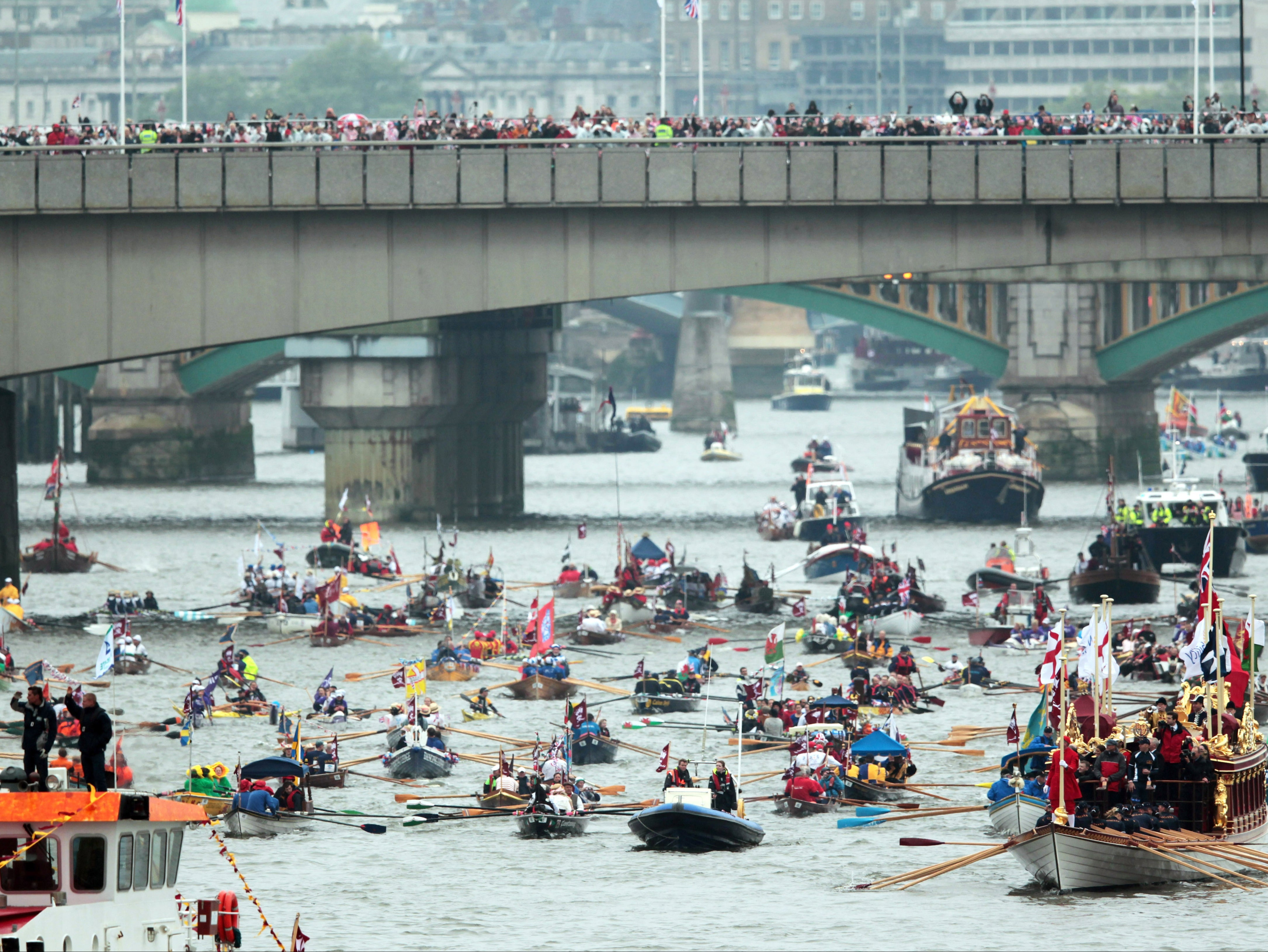 Rowbarge Gloriana (R) leads the manpowered section past HMS Belfast (L) of the Diamond Jubilee River Pageant during the Queen Elizabeth's Diamond Jubilee Pageant on the River Thames in London