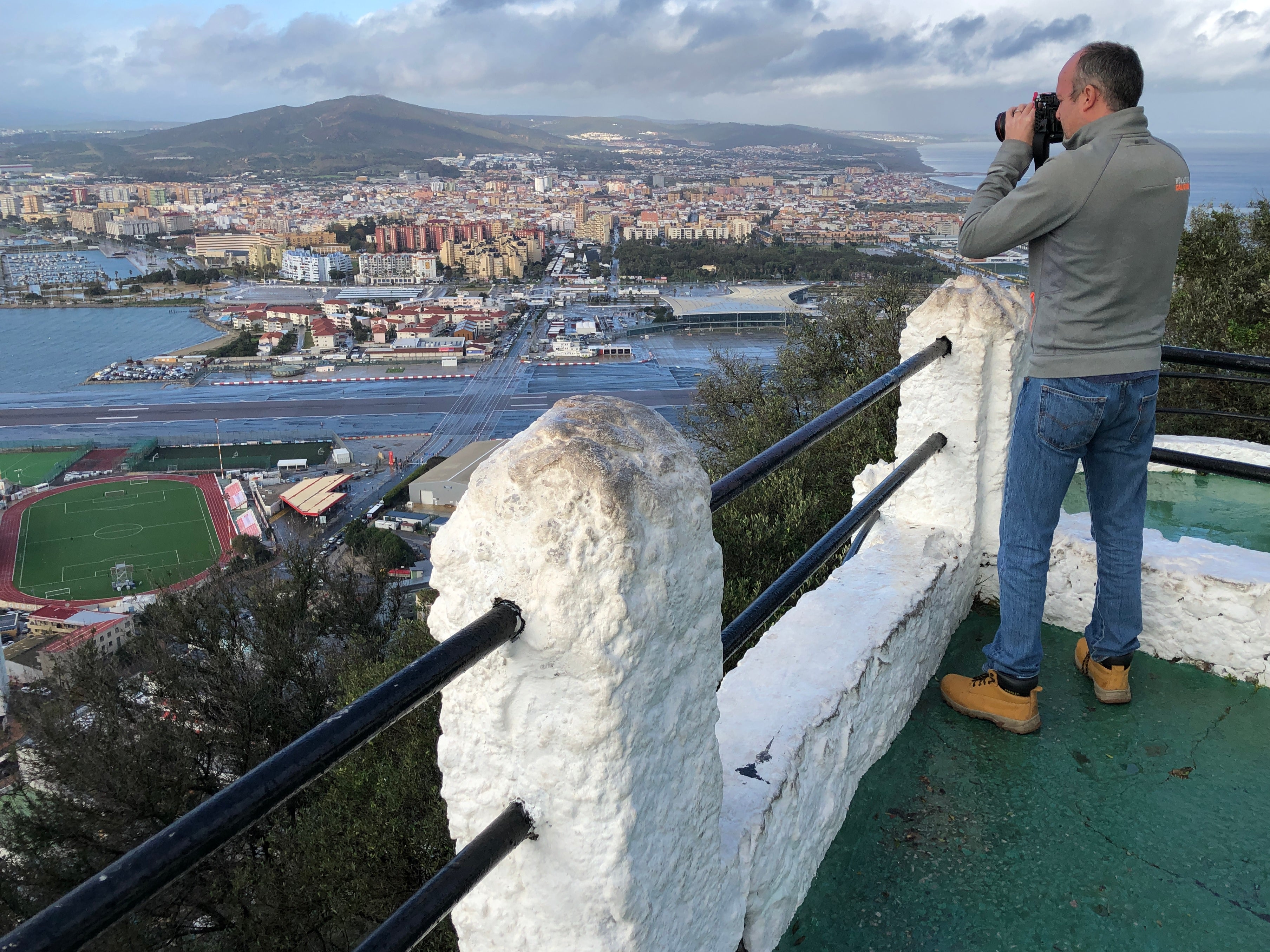 Multinational view: photographer on an outcrop of the Rock of Gibraltar, overlooking the airport runway and southern Spain